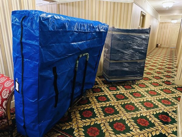 A mattress in a zipped moving bag and a stretch-wrapped dresser waiting in a building hallway