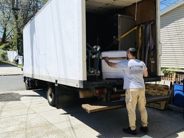 A mover loading an appliance onto our truck on a Queens side street